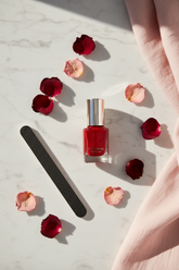 Smalto rosso professionale lifestyle flat lay su marmo bianco con petali di rosa